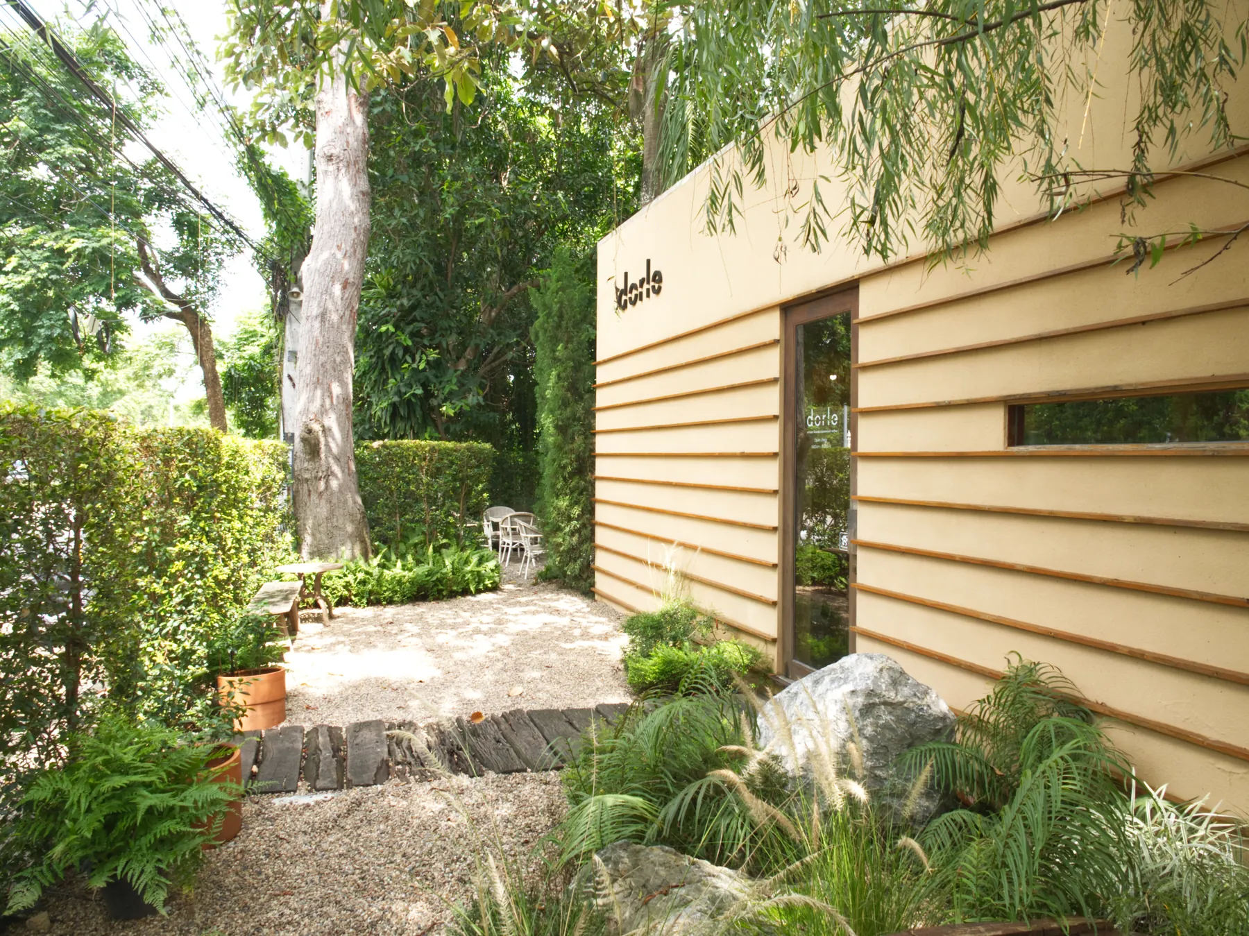 Dorle café entrance surrounded by mature greenery